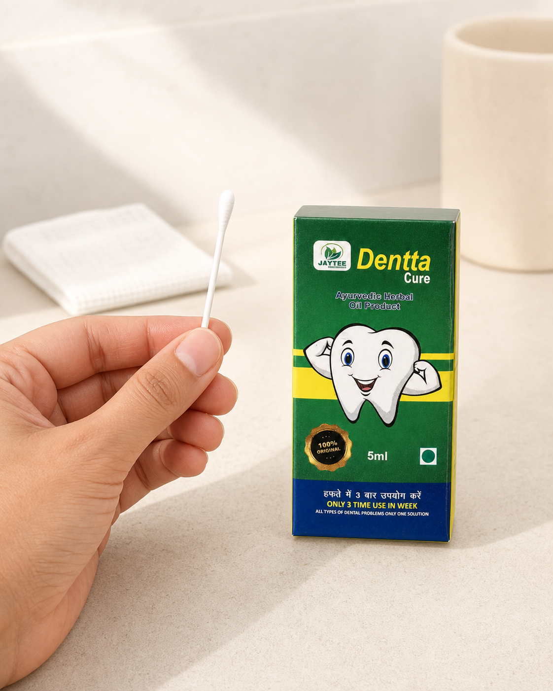 Adult hand holding a clean cotton earbud beside a closed Dentta Cure 5 ml box