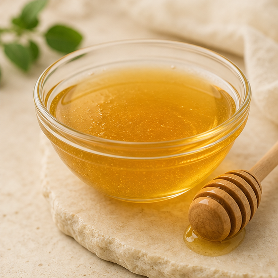 Golden honey in a glass bowl with a wooden dipper in an editorial ingredient study