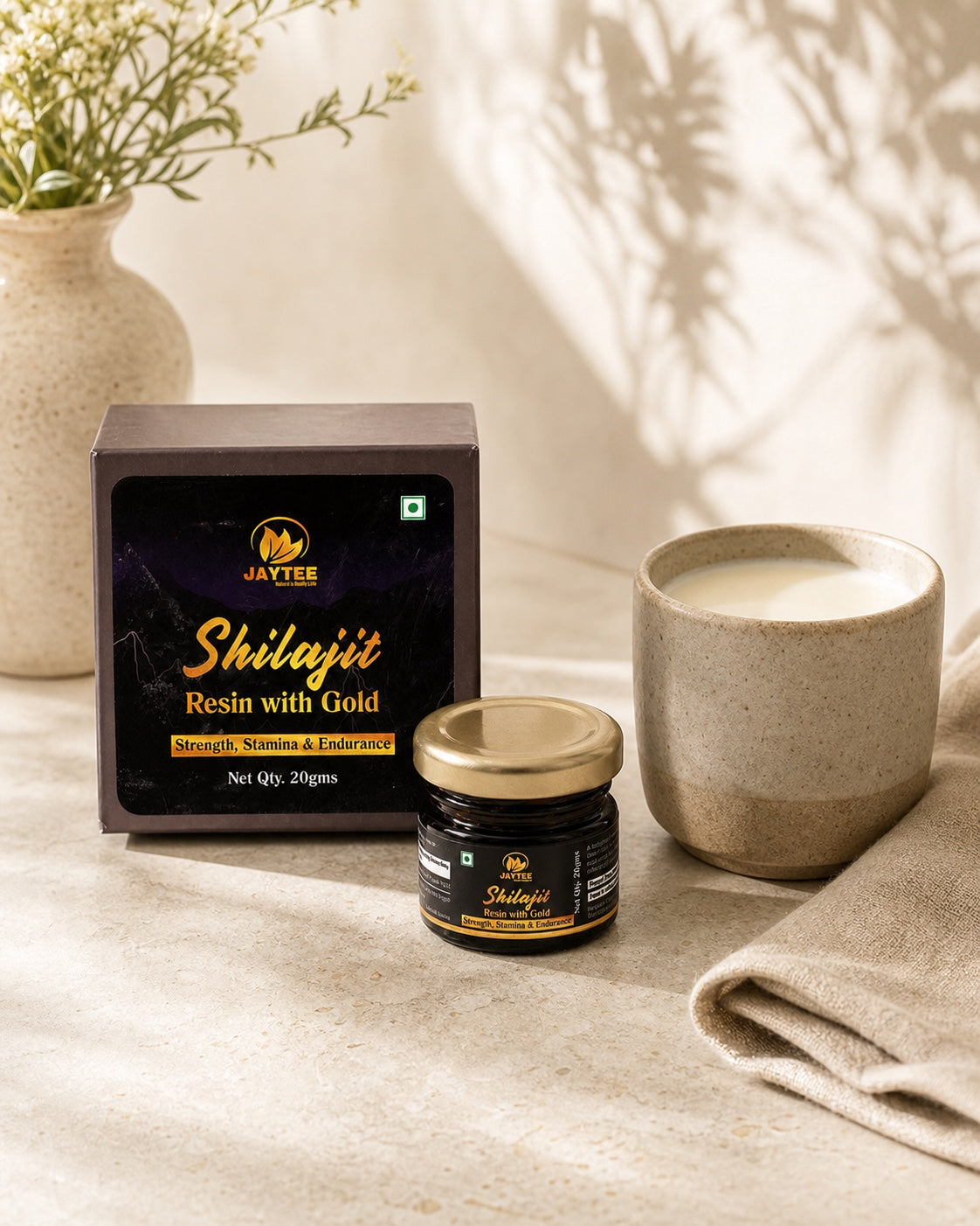 Closed Shilajit Resin with Gold 20 g jar and box beside a ceramic cup of warm milk
