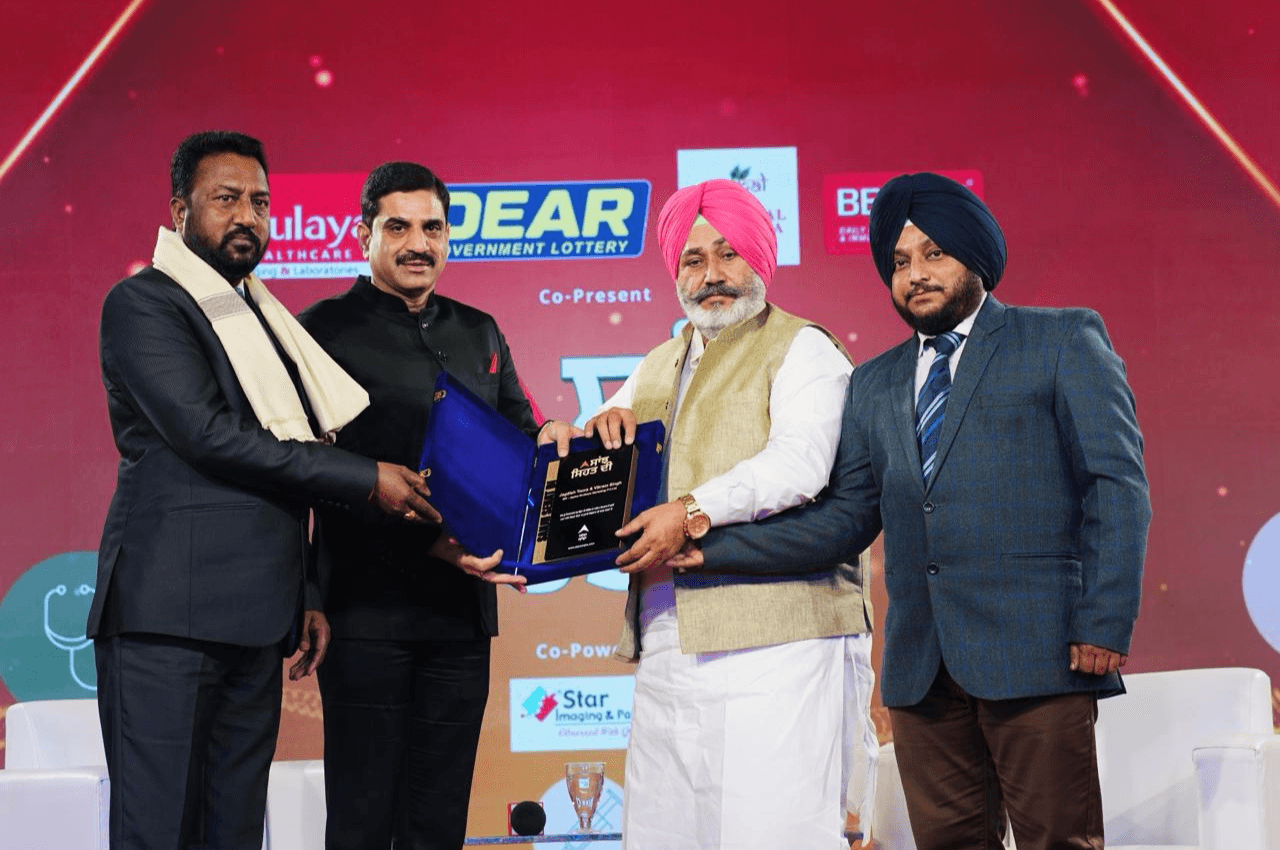 Four men at an award presentation, with a plaque being presented on stage